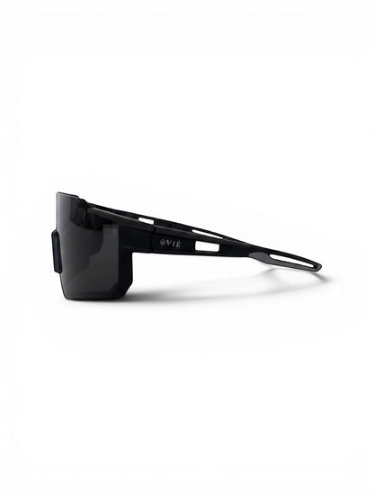 EVIE EYEWEAR black sport sunglasses with a wraparound design and grey accents on the temples, resting on a grey textured surface.