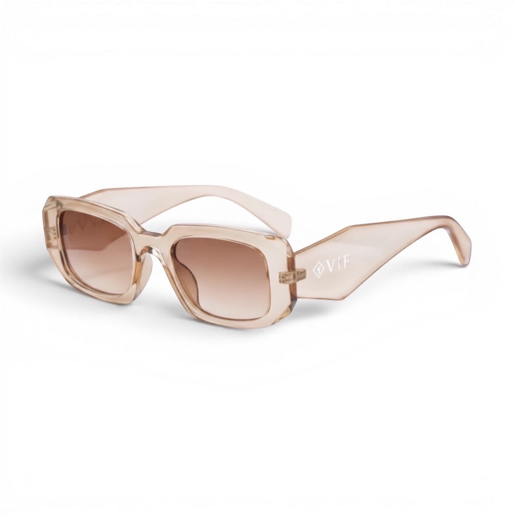 Gafas de sol transparentes de color melocotón de EVIE EYEWEAR con lentes degradadas marrones y montura rectangular gruesa.